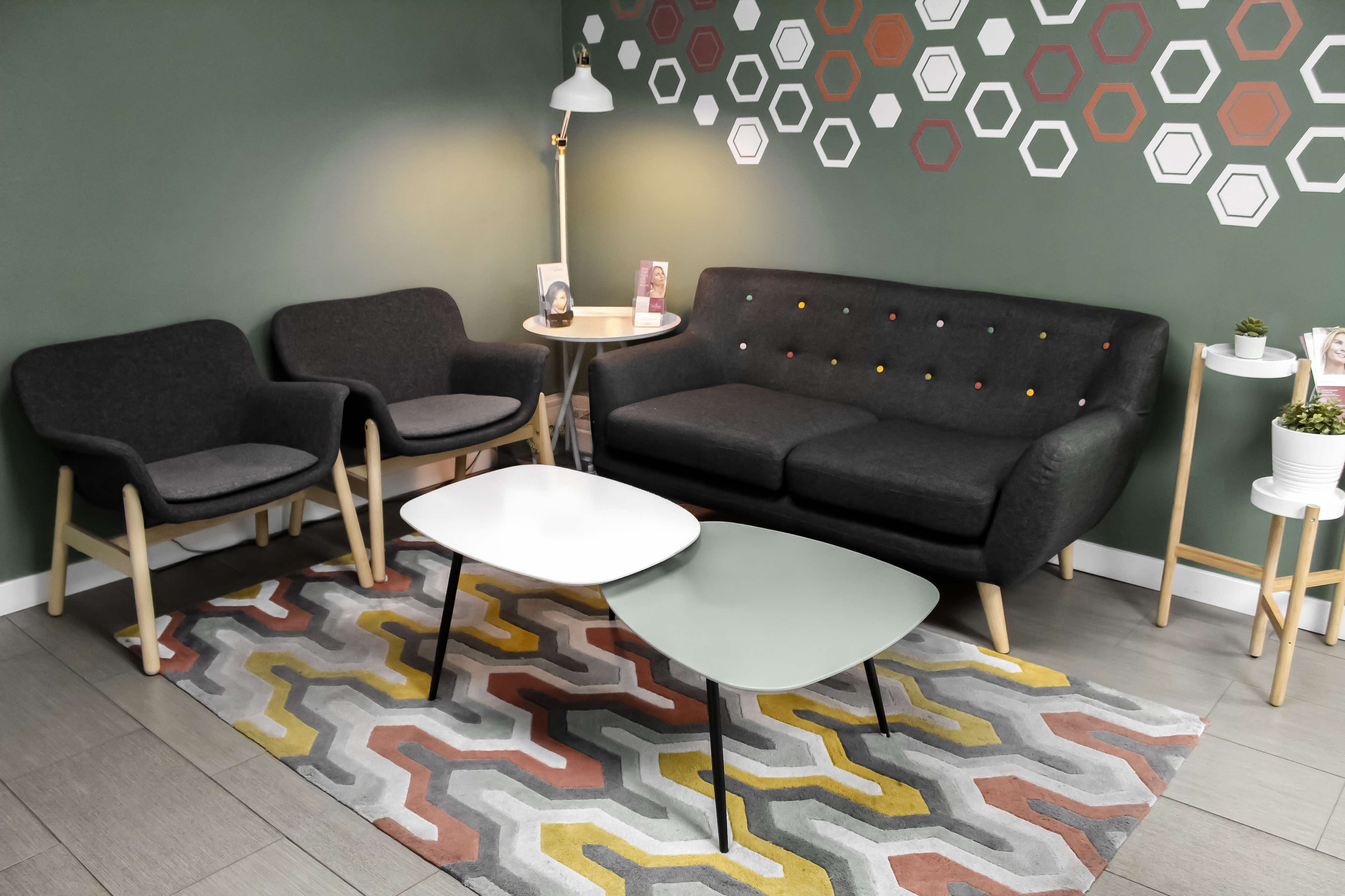 The Evolved Medical waiting room — grey armchairs and a sofa under a wall of white and terracotta hexagons