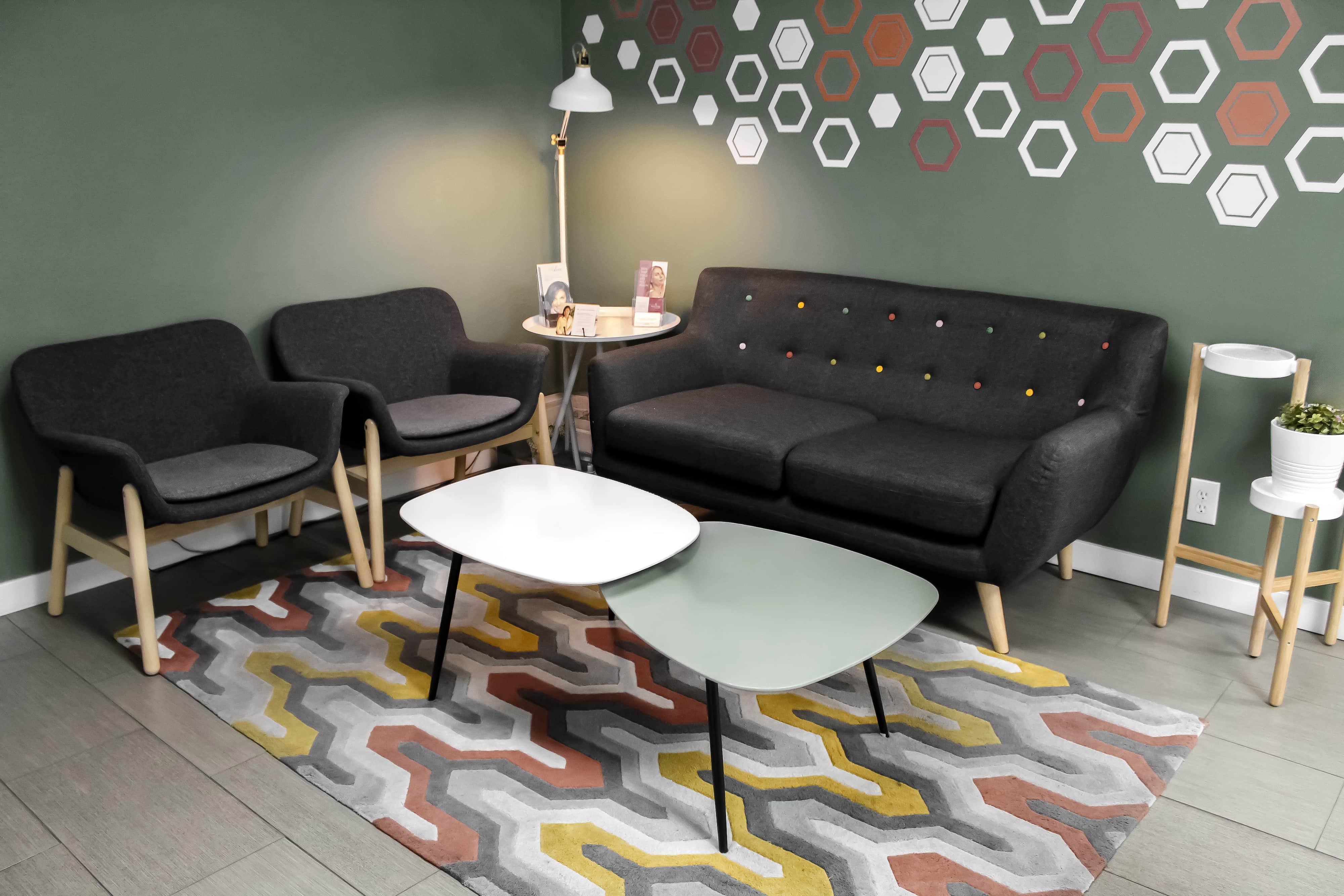 The Evolved Medical waiting room — grey armchairs and a sofa under a wall of white and terracotta hexagons