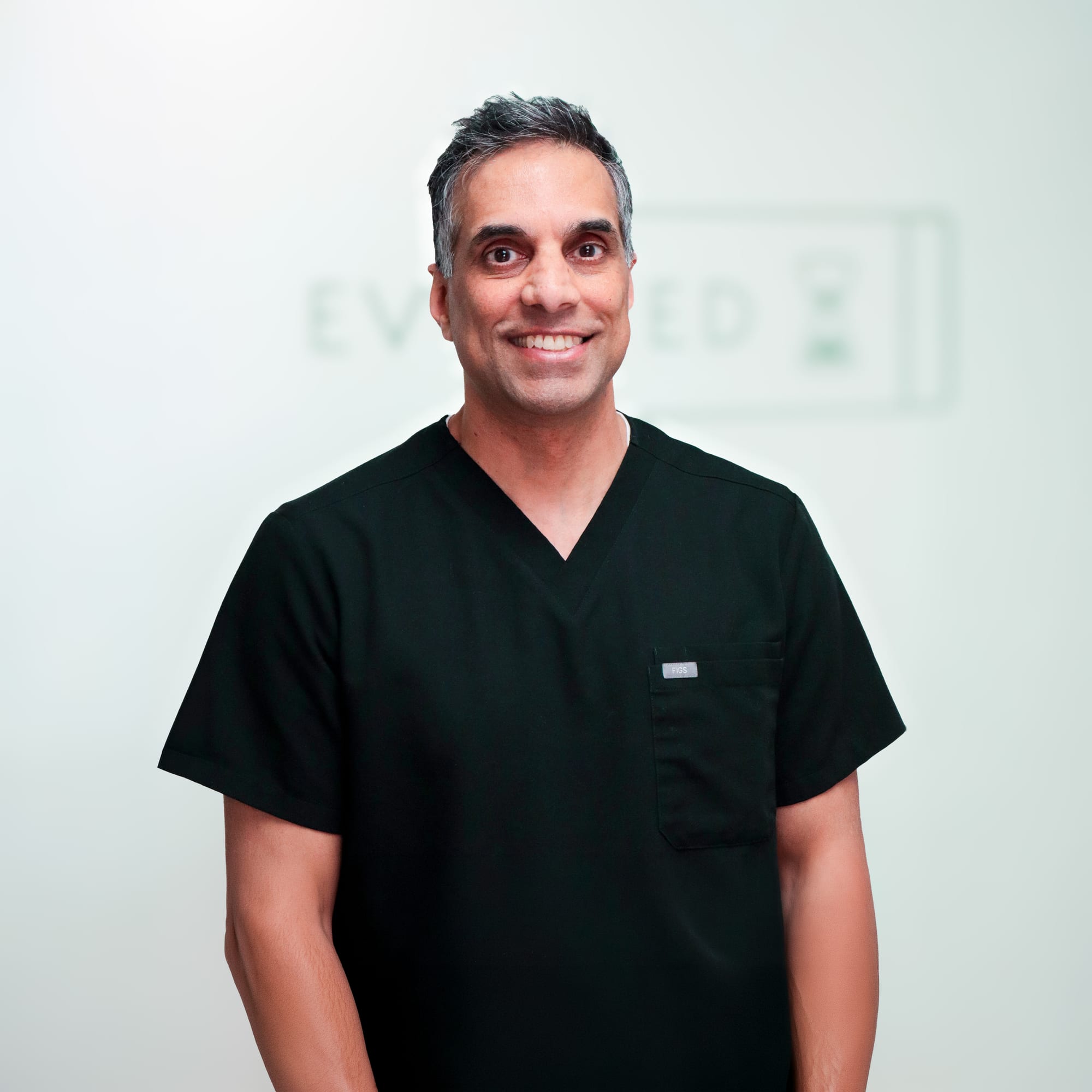 Dr. Amit Rajguru smiling in dark scrubs at Evolved Medical