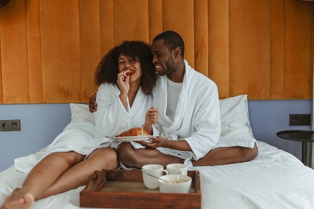 Couple in bathrobes sharing breakfast in bed &mdash; sexual wellness at Evolved Medical
